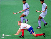 British forward Mark Pearn attempts a reverse hit as Tirkey and Gill watch. Allsport/Shaun Botterill