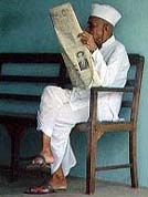 Old man on chair reading newspaper